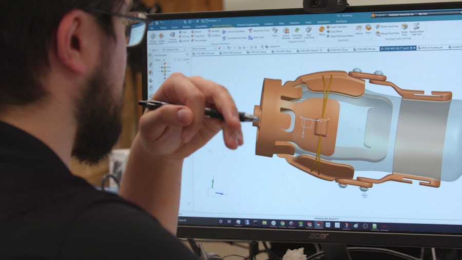 A man models a machine part on a computer screen