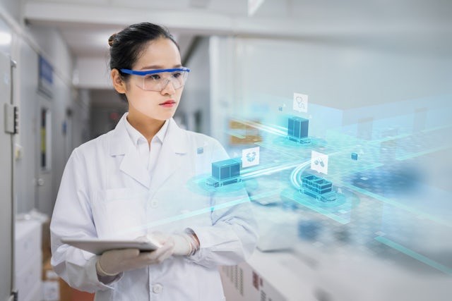 A woman wearing safety glasses visualizes a digital image overlaid inside her laboratory environment.