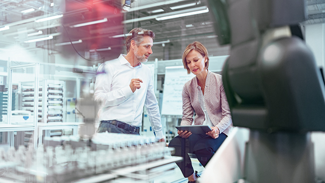 两个人在实验室工作，在平板电脑上查看工业物联网数据。