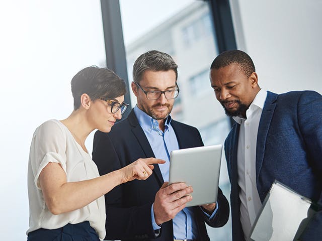 Three business people making data-supported decisions using a tablet.