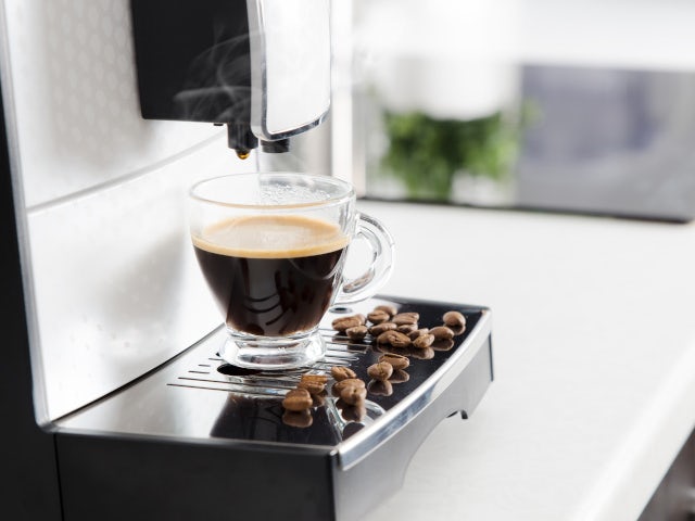 Image of a an espresso maker with a cup of a espresso and coffee beans.