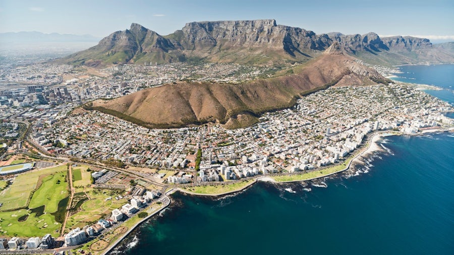 Aerial view of Cape Town, South Africa, featuring Table Mountain, surrounding urban areas, and the Atlantic coastline.
