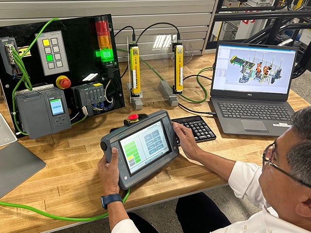Engineer with an HMI, a PLC and process simulation software conducting virtual commissioning.