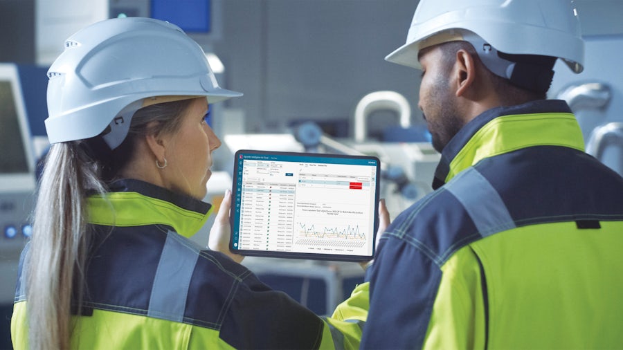 Dos ingenieros miran una tableta y analizan los datos de consumo energético de un proceso de fabricación.