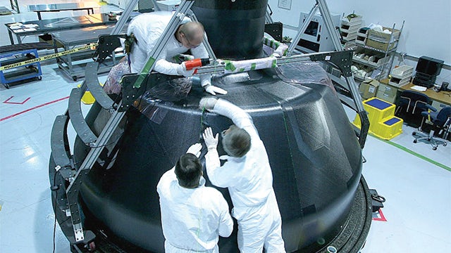 Pictured is the installation of ply segments during layup of the inner honeycomb sandwich skin at ATK in Iuka, Mississippi, USA. The composite plies are being laid up with the assistance of a laser projection system (as indicated by the feint green lines on the top and side of the capsule), which is driven by Fibersim software. The Laser Projection module in Fibersim enables engineers to automatically generate laser data files from within their computer-aided design (CAD) system directly from the 3D model of the composite part. This significantly increases engineering productivity, reduces errors and makes updating and maintaining laser projection data easy