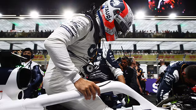 A racecar driver wearing a helmet gets into a car